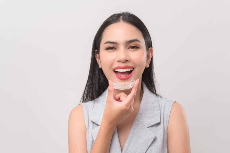 Young,Smiling,Woman,Holding,Invisalign,Braces,In,Studio,,Dental,Healthcare